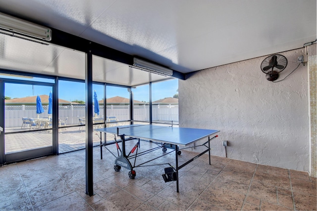 game room featuring a mountain view, a wall mounted air conditioner, and a wall of windows