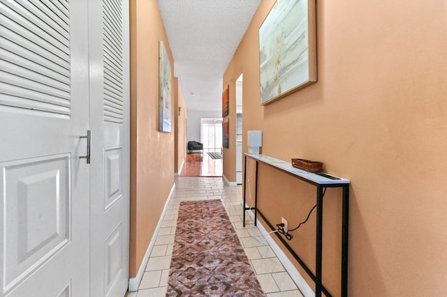 hall with light tile patterned floors and a textured ceiling