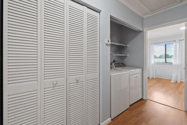 laundry area with independent washer and dryer, ornamental molding, and light wood-type flooring