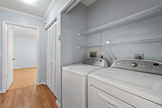 laundry area with washing machine and dryer, ornamental molding, and light wood-type flooring