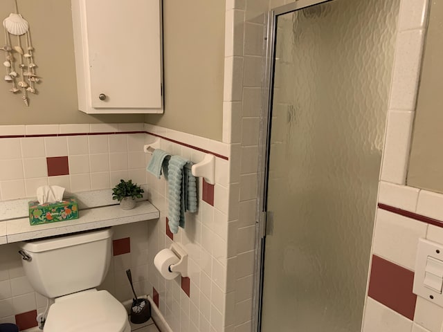 bathroom with toilet, an enclosed shower, and tile walls