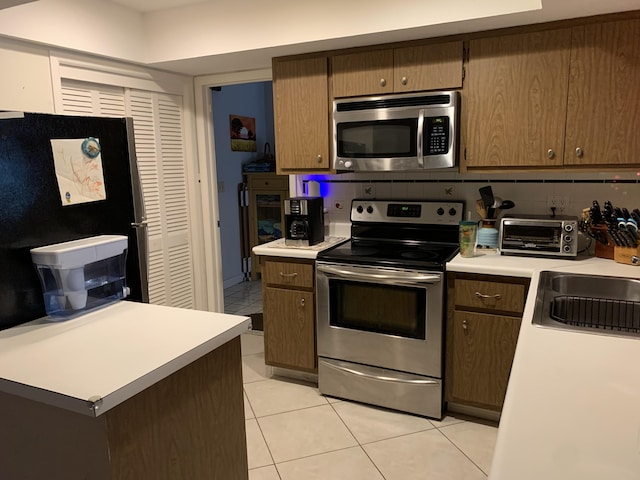 kitchen with light tile patterned floors, backsplash, stainless steel appliances, and sink