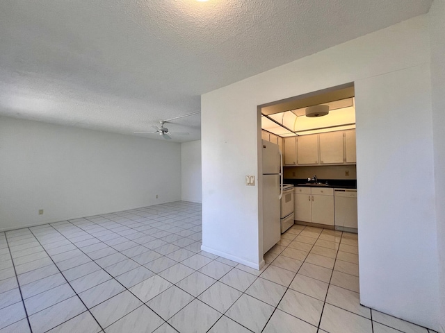 kitchen with sink, a textured ceiling, white appliances, and cream cabinets