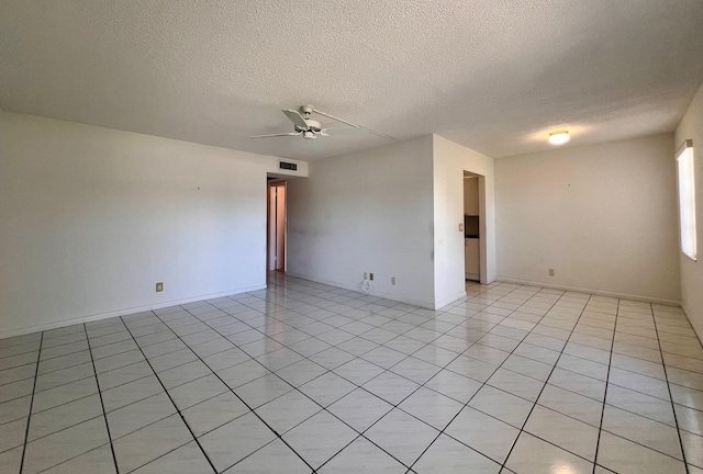 empty room with ceiling fan, light tile patterned floors, and a textured ceiling