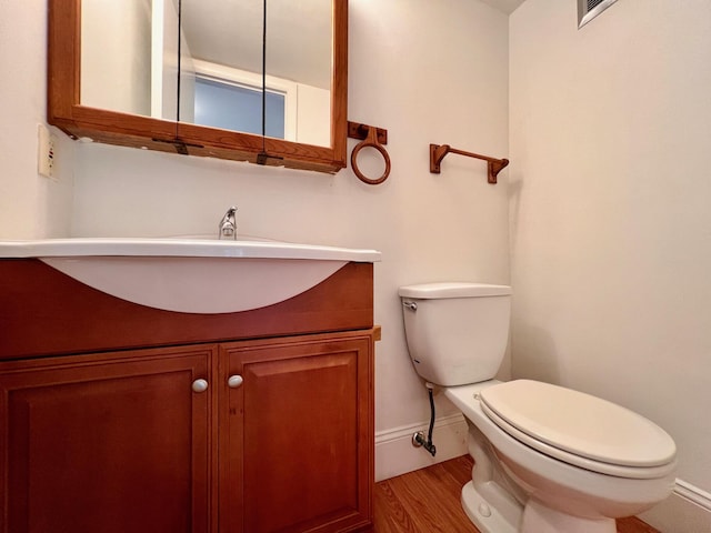 bathroom featuring wood-type flooring, vanity, and toilet