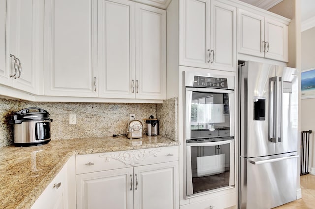 kitchen with light stone countertops, appliances with stainless steel finishes, tasteful backsplash, crown molding, and white cabinets