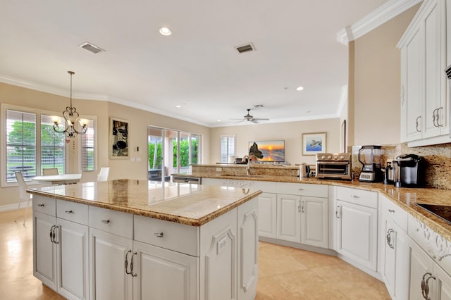 kitchen with a center island, white cabinets, hanging light fixtures, and ceiling fan with notable chandelier