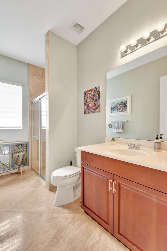 bathroom featuring a shower with door, vanity, and toilet