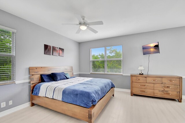 bedroom featuring ceiling fan, light hardwood / wood-style flooring, and multiple windows