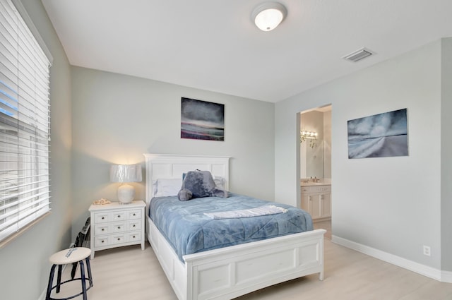 bedroom featuring ensuite bathroom, light wood-type flooring, and sink