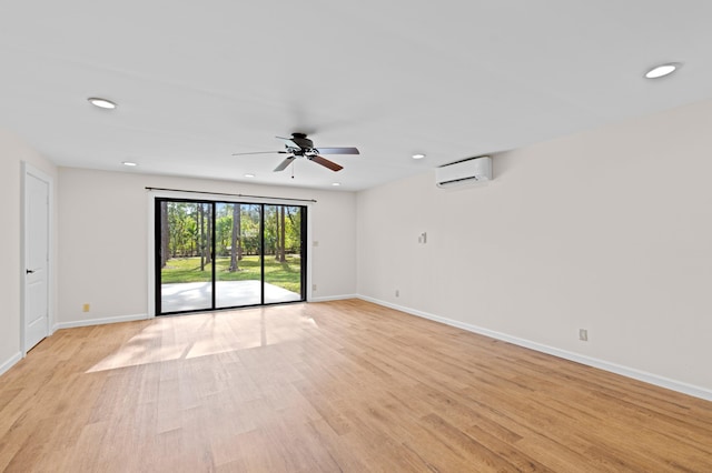 unfurnished room featuring a wall mounted AC, ceiling fan, and light hardwood / wood-style flooring