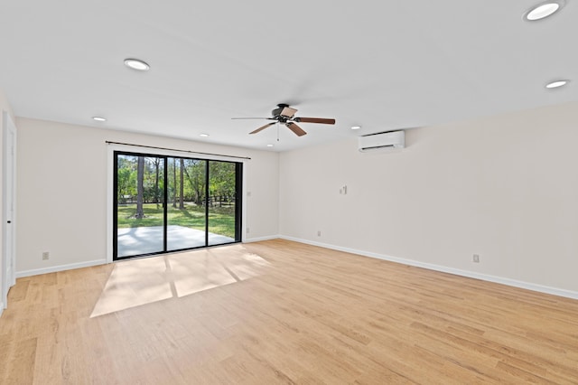 empty room featuring an AC wall unit, ceiling fan, and light wood-type flooring