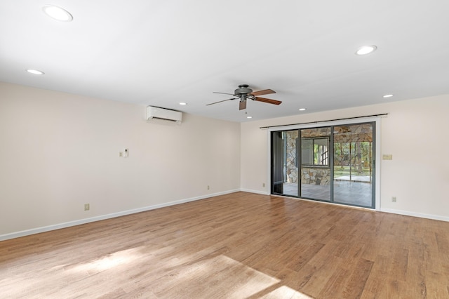 empty room featuring ceiling fan, a wall mounted air conditioner, and light hardwood / wood-style flooring