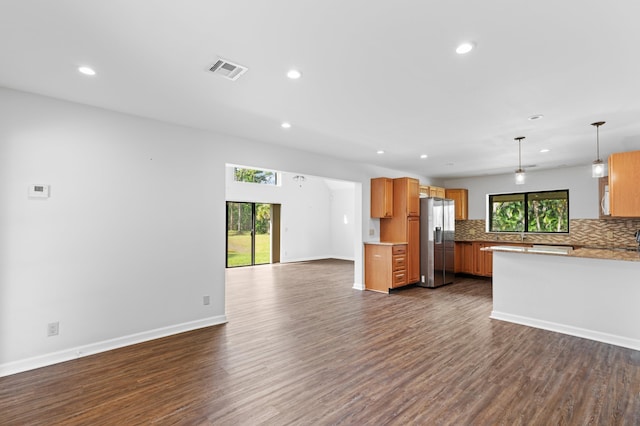 kitchen featuring a wealth of natural light, hanging light fixtures, backsplash, and stainless steel refrigerator with ice dispenser