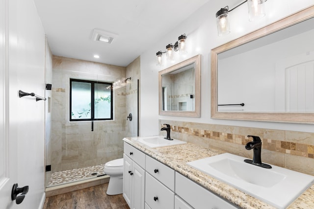 bathroom with hardwood / wood-style floors, toilet, walk in shower, vanity, and decorative backsplash