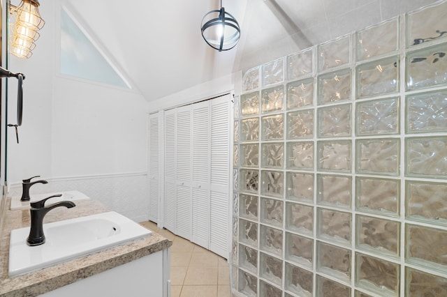 bathroom with a shower, vanity, tile patterned flooring, and vaulted ceiling