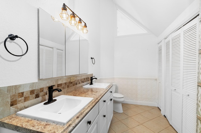 bathroom featuring lofted ceiling, tile patterned flooring, vanity, and toilet