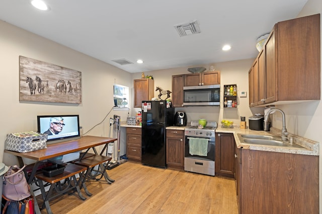 kitchen with appliances with stainless steel finishes, light hardwood / wood-style floors, and sink