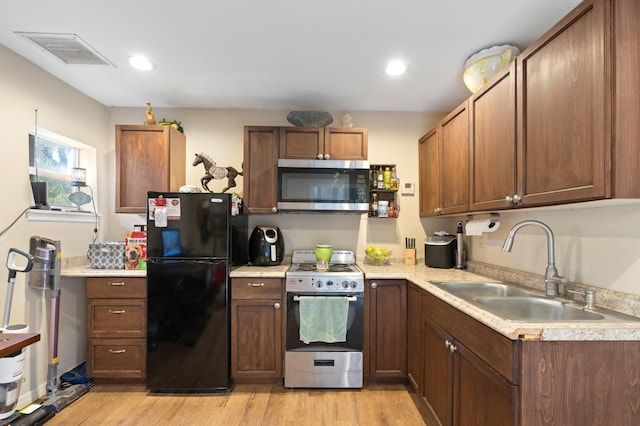 kitchen with stainless steel appliances, light wood-type flooring, and sink