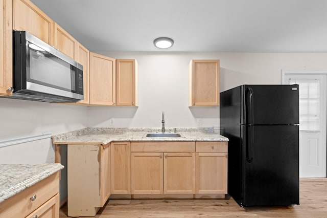 kitchen with black fridge, light hardwood / wood-style floors, sink, and light brown cabinetry