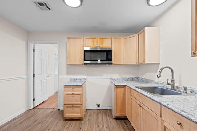 kitchen featuring sink, light hardwood / wood-style flooring, light stone countertops, and light brown cabinets