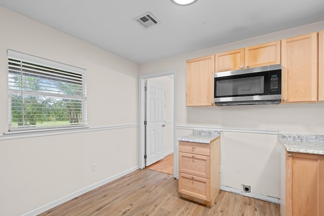 kitchen featuring light hardwood / wood-style flooring, light stone countertops, and light brown cabinets