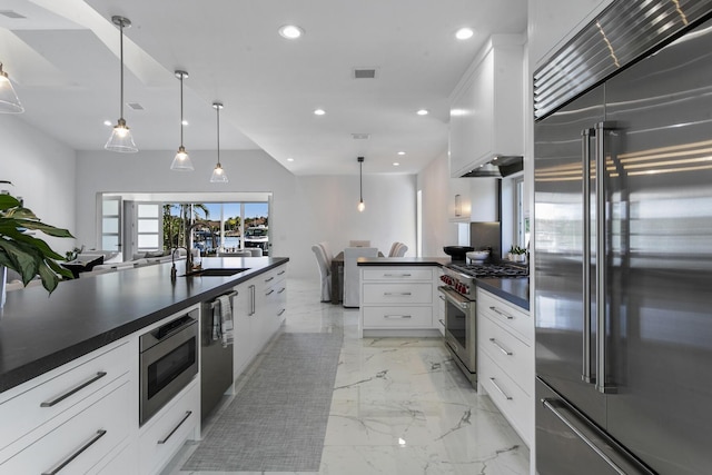 kitchen with high quality appliances, white cabinetry, hanging light fixtures, and sink