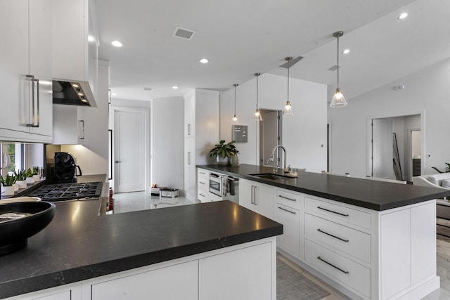 kitchen with a large island, white cabinetry, sink, and decorative light fixtures