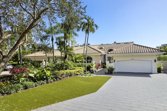 mediterranean / spanish-style home with a garage and a front lawn