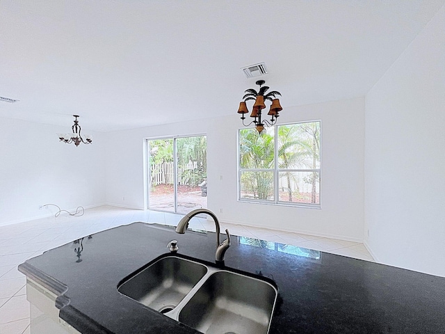 kitchen with light tile patterned floors, a wealth of natural light, a notable chandelier, and sink