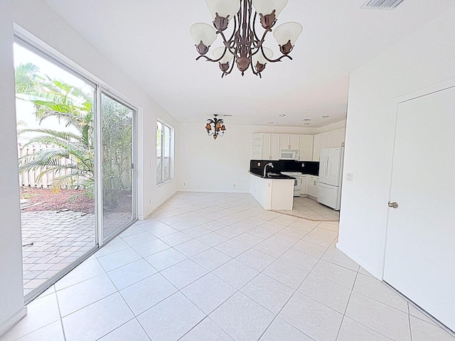 unfurnished living room with a notable chandelier and light tile patterned flooring