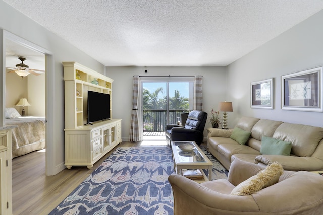 living room with ceiling fan, light hardwood / wood-style floors, and a textured ceiling