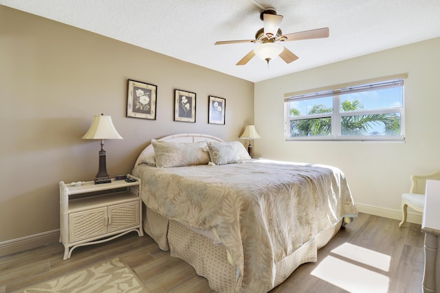 bedroom with ceiling fan, wood-type flooring, and a textured ceiling