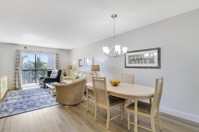 dining area featuring hardwood / wood-style floors, a textured ceiling, and an inviting chandelier