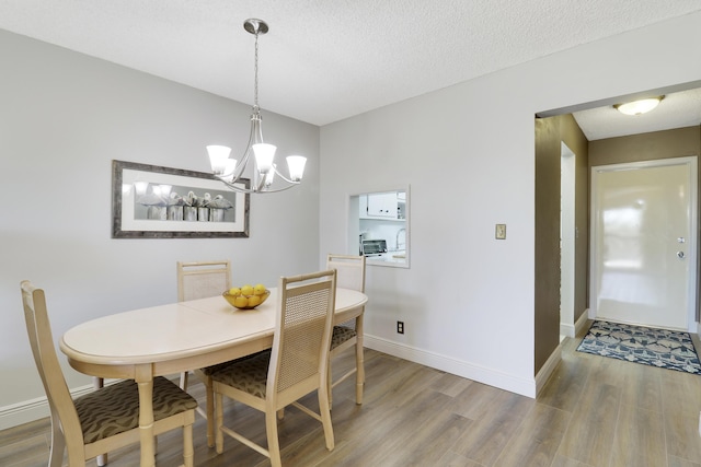 dining area featuring sink, a chandelier, a textured ceiling, and hardwood / wood-style flooring