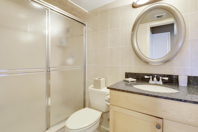 bathroom featuring vanity, decorative backsplash, toilet, tile walls, and a shower with shower door