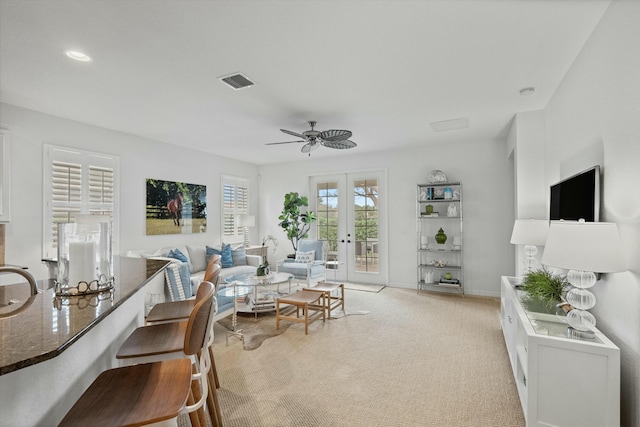 living room featuring ceiling fan, light colored carpet, and french doors