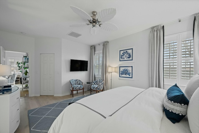 bedroom with light wood-type flooring, ceiling fan, and multiple windows