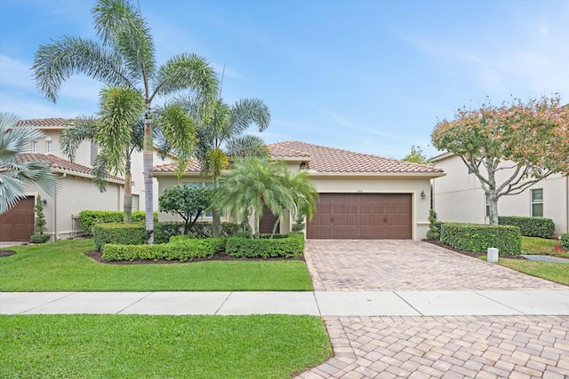 mediterranean / spanish-style home featuring a front lawn and a garage