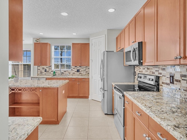 kitchen featuring light stone countertops, sink, tasteful backsplash, light tile patterned floors, and appliances with stainless steel finishes