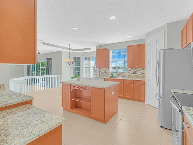 kitchen featuring a center island, electric stove, sink, hanging light fixtures, and light stone countertops