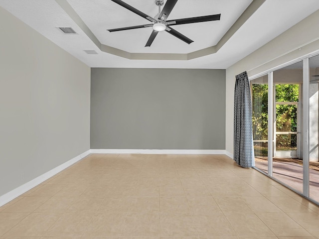 tiled spare room featuring a tray ceiling and ceiling fan