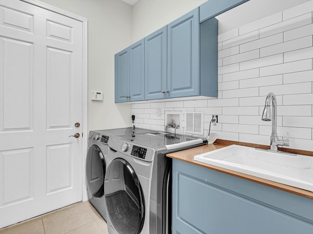 washroom with cabinets, light tile patterned floors, sink, and washing machine and dryer