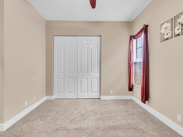 unfurnished bedroom with carpet floors, a closet, and ceiling fan