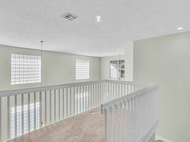 hall with carpet floors and a textured ceiling