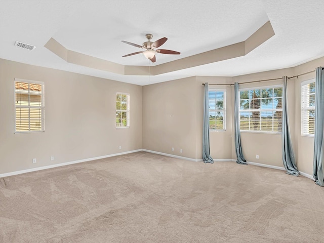 unfurnished room with plenty of natural light, ceiling fan, and a tray ceiling