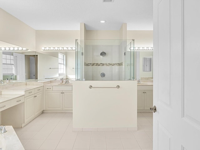 bathroom featuring tile patterned flooring, vanity, and tiled shower