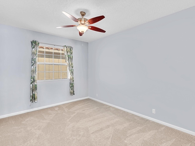 empty room featuring ceiling fan, light colored carpet, and a textured ceiling