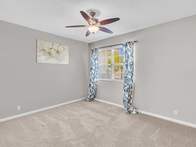 empty room with ceiling fan, light carpet, and a textured ceiling