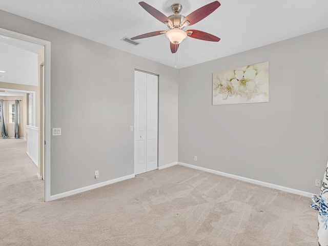 unfurnished bedroom featuring ceiling fan, light carpet, and a closet